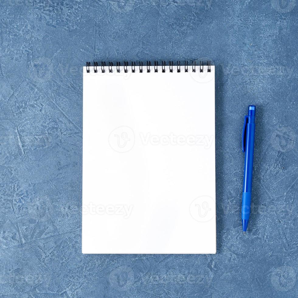 o bloco de notas aberto com página branca limpa na mesa de pedra azul escura envelhecida, vista superior foto