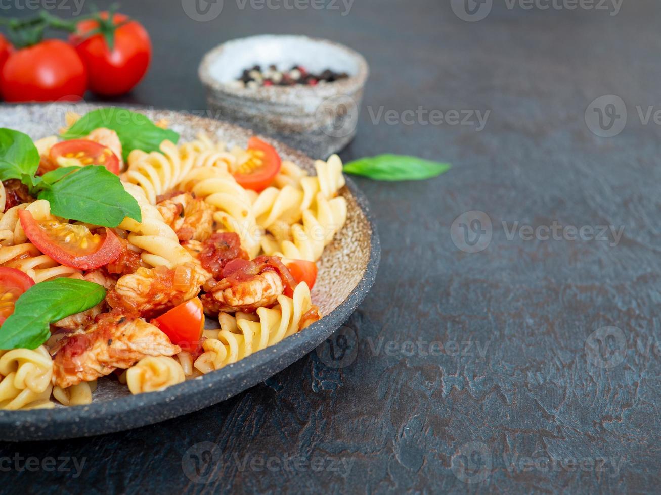 massa fusilli com molho de tomate, filé de frango com folhas de manjericão foto