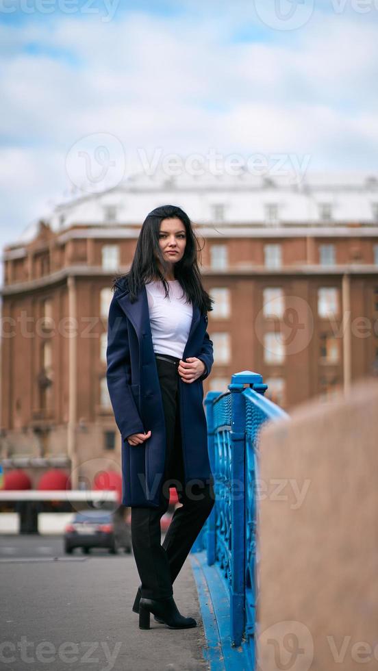 encantadora mulher pensativa elegantemente vestida com longos cabelos escuros viaja pela europa, em pé no centro da cidade de st. petersburgo. uma linda garota vaga sozinha pelas ruas de outono foto