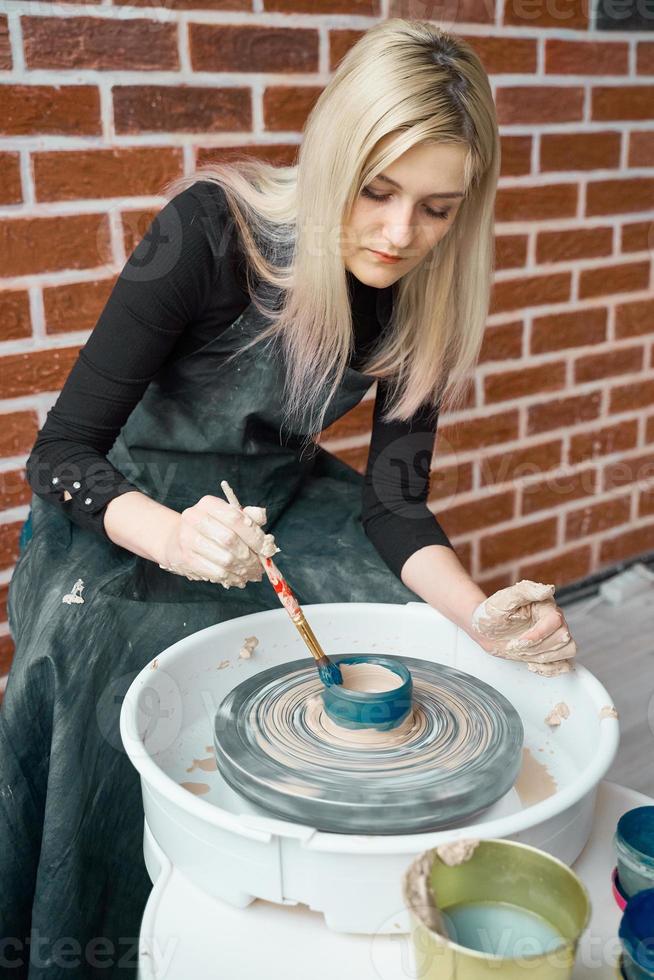 mulher feliz fazendo cerâmica na roda, pinta azul. conceito para mulher em freelance, negócios. produto artesanal. ganhar dinheiro extra, agitação lateral, transformando hobbies em dinheiro e paixão em trabalho foto