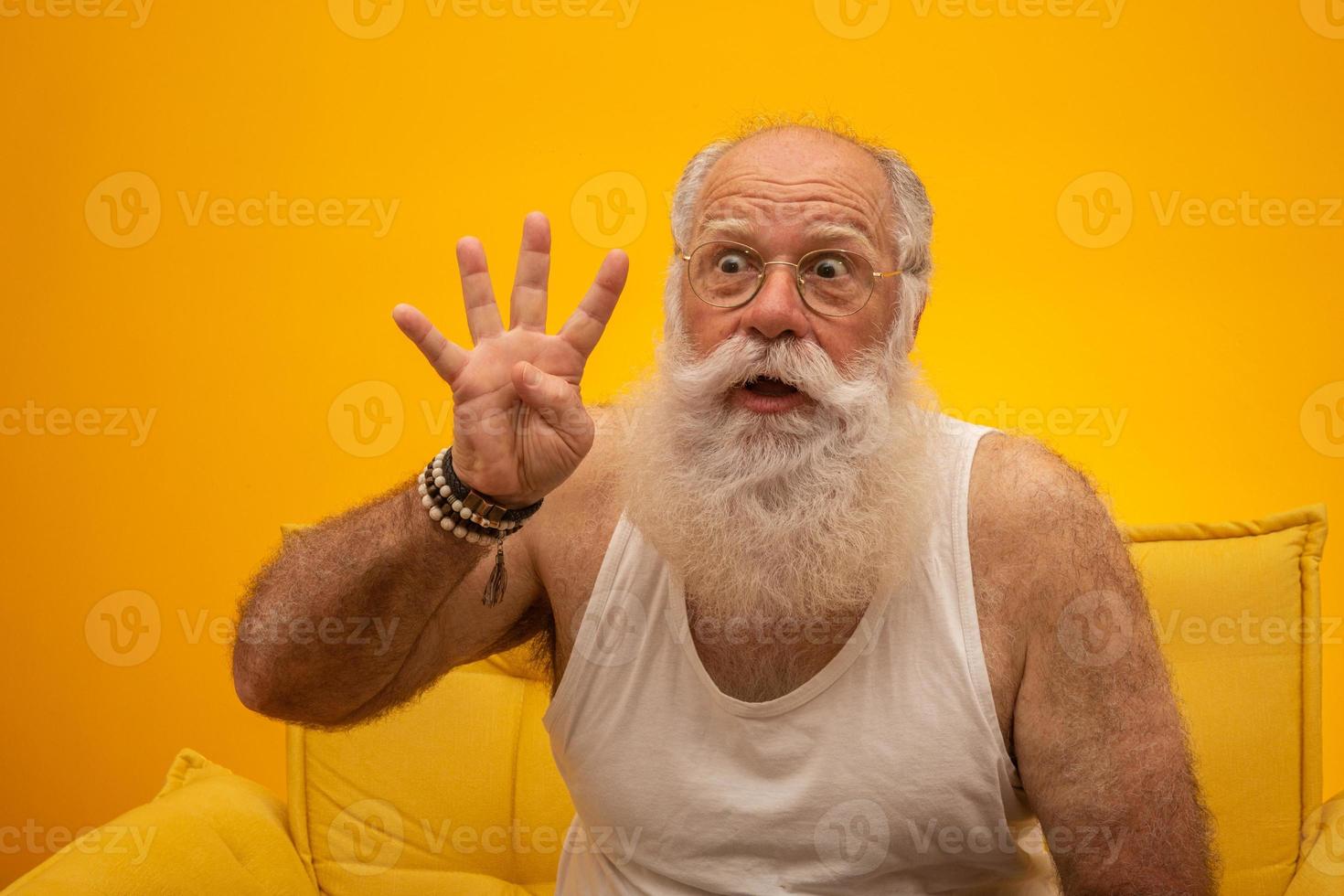 sorrindo sênior com um homem de longa barba branca fazendo quatro vezes sinal de gesto com os dedos da mão sobre fundo amarelo. sentimentos de expressão facial de emoção positiva, atitude, símbolo, contagem regressiva. foto