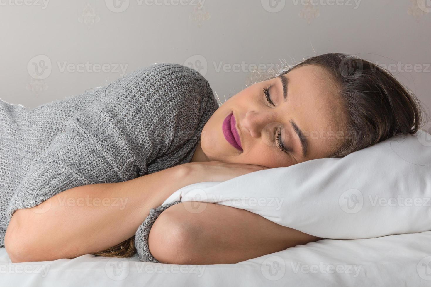 linda mulher dormindo no travesseiro confortável na cama em casa foto
