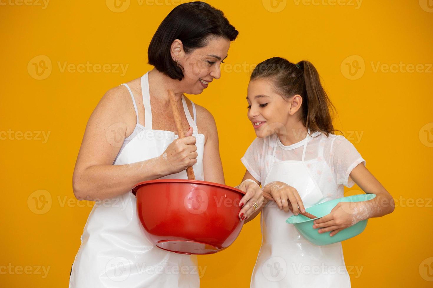 conceito de dia das mães. filha e mãe preparando uma receita em fundo amarelo foto