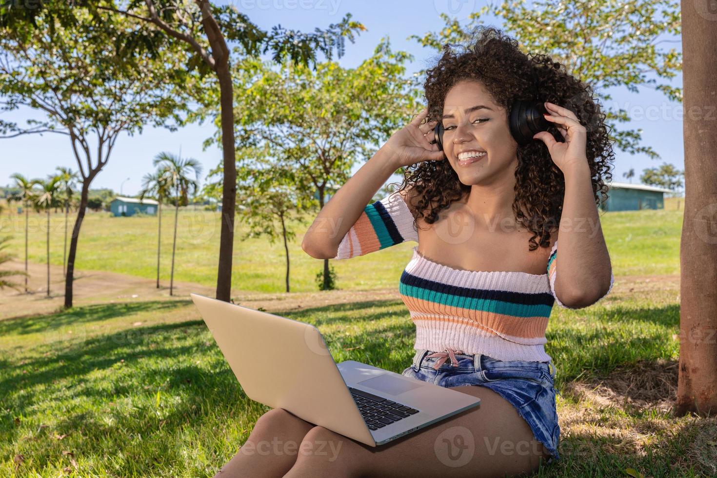 linda garota afro-americana ouvindo música no laptop em um parque foto