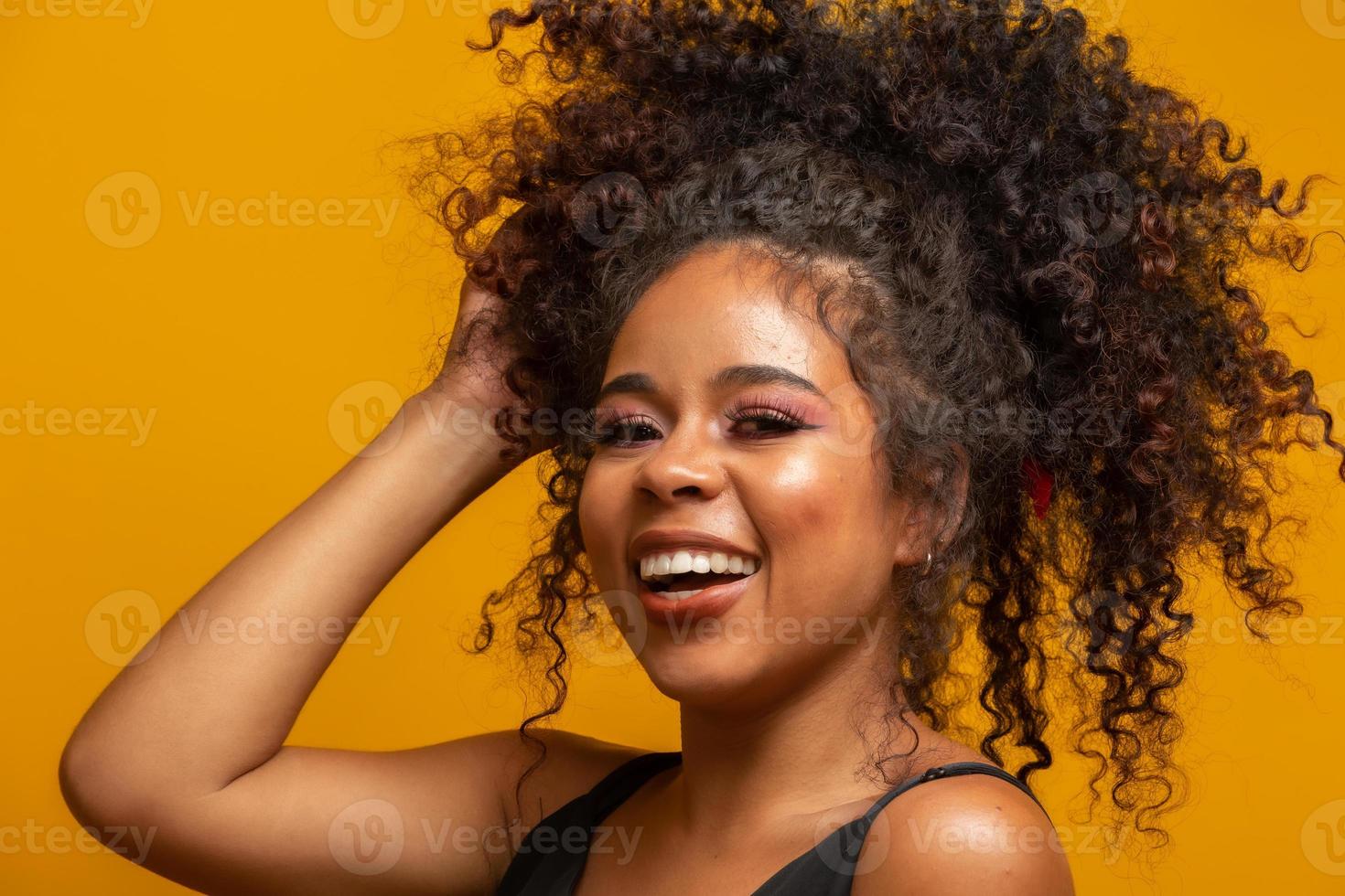 retrato da beleza da mulher afro-americana com penteado afro e maquiagem glamour. mulher brasileira. mestiço. cabelo encaracolado. Penteado. fundo amarelo. foto