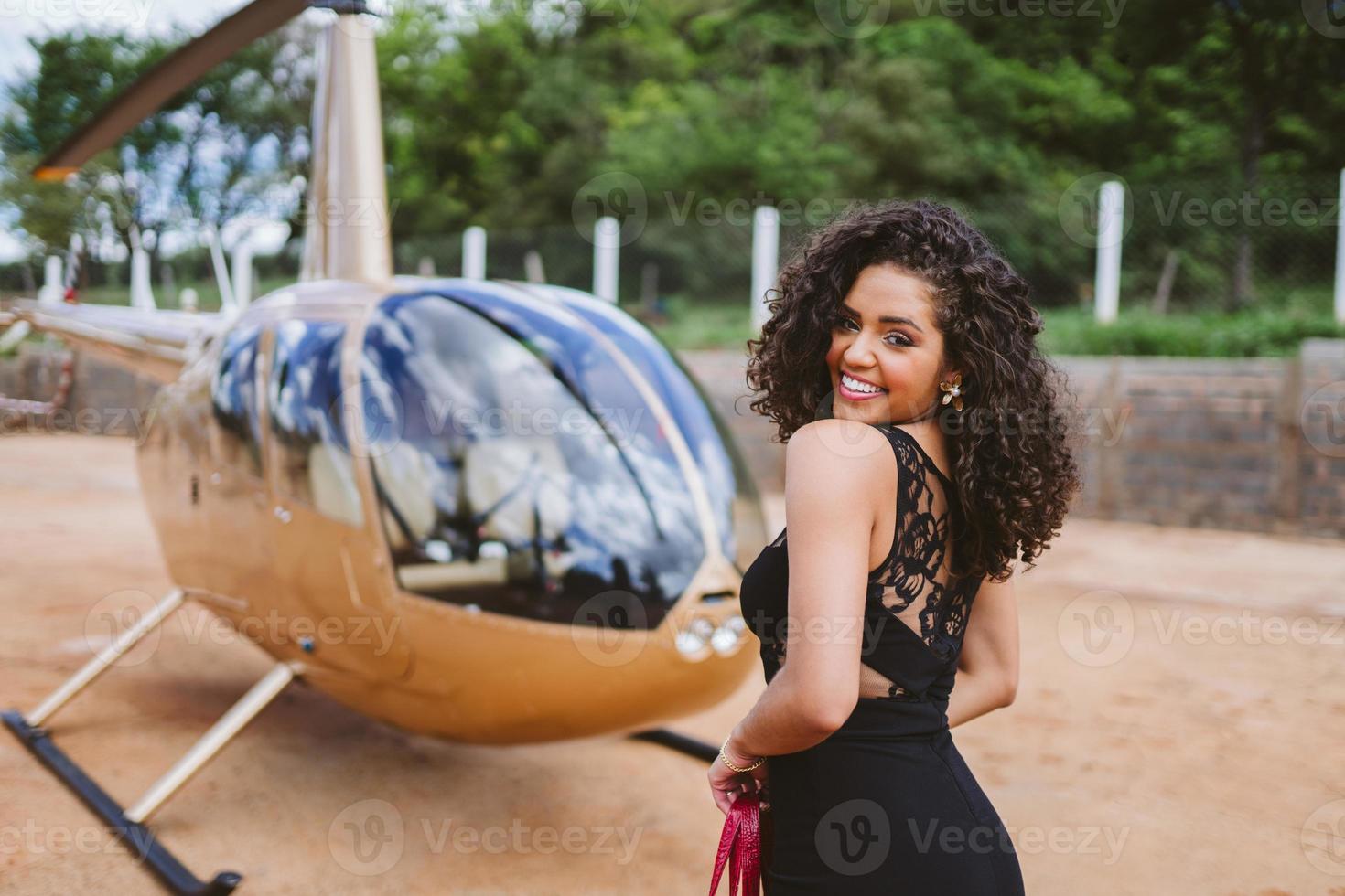 bem sucedida inteligente elegante jovem Latina perto de helicóptero. conceito de estilo de vida de luxo foto