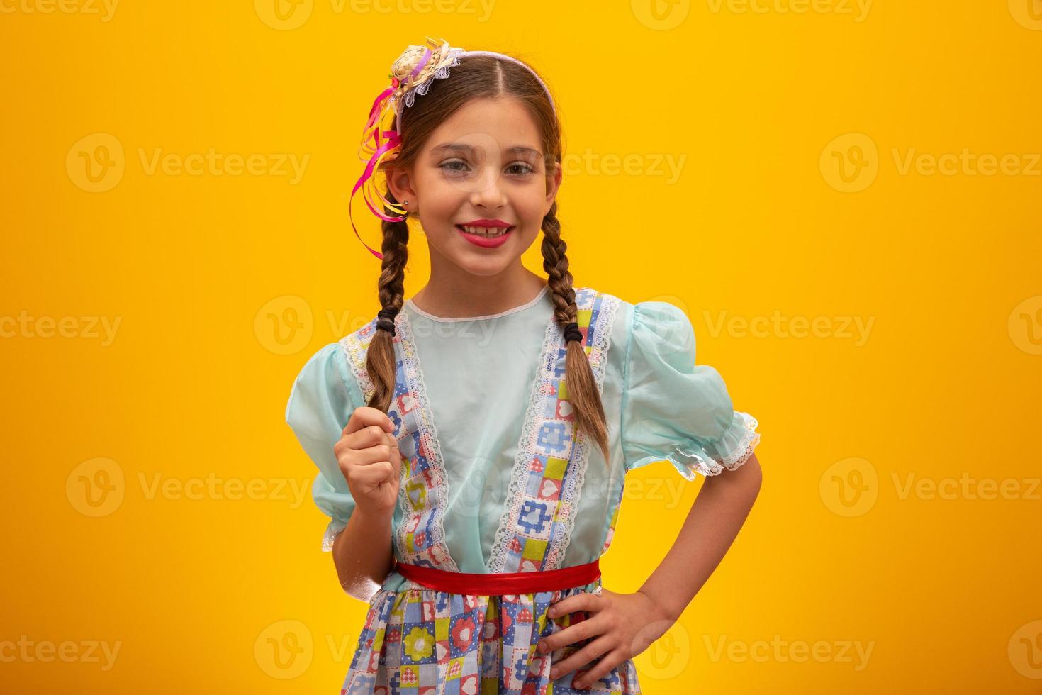 criança em roupas típicas da famosa festa brasileira chamada festa junina em comemoração a são joao. linda garota em fundo amarelo. foto