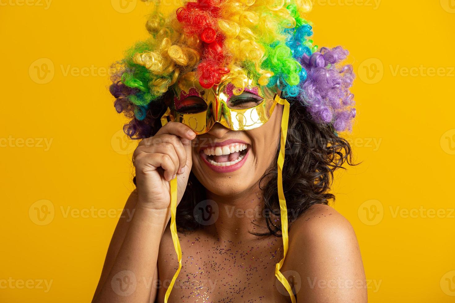 linda mulher vestida para a noite de carnaval. mulher sorridente pronta para curtir o carnaval com uma peruca colorida e máscara foto