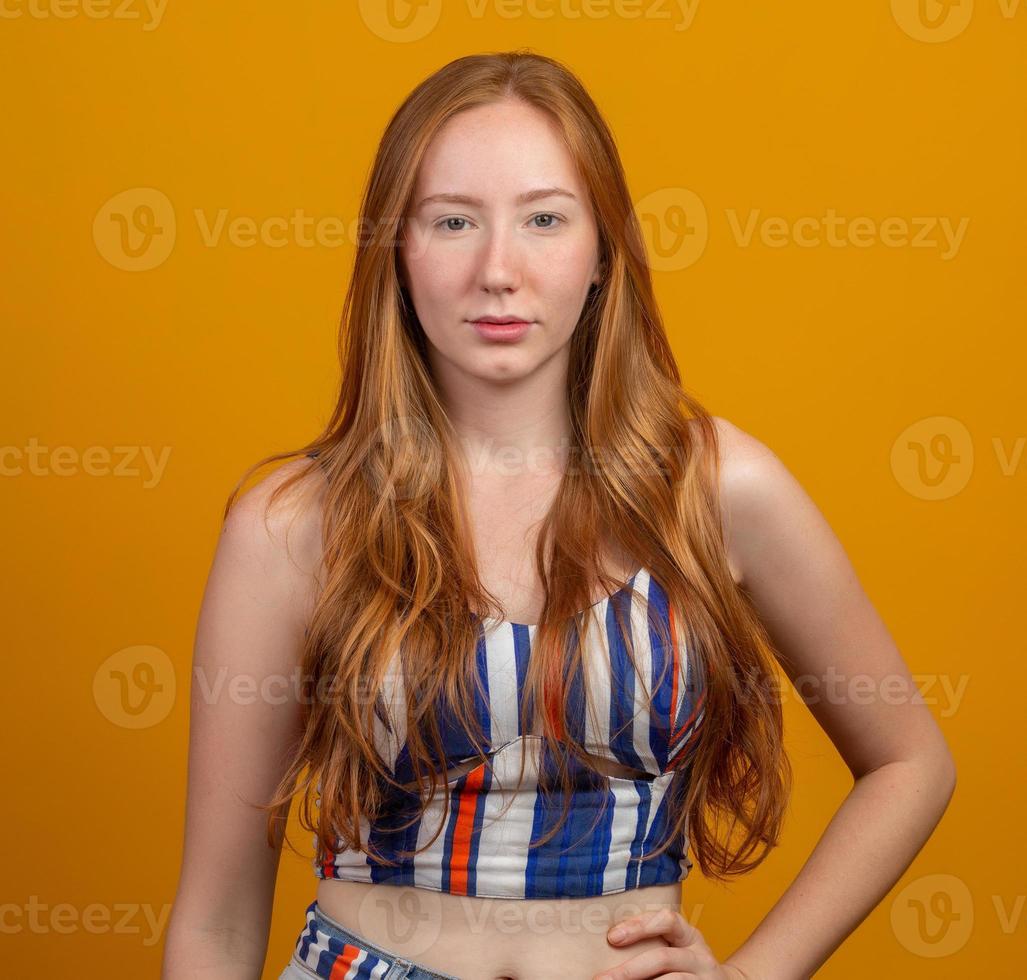 retrato de linda ruiva alegre com cabelo a voar sorrindo rindo olhando para a câmera sobre fundo amarelo. foto