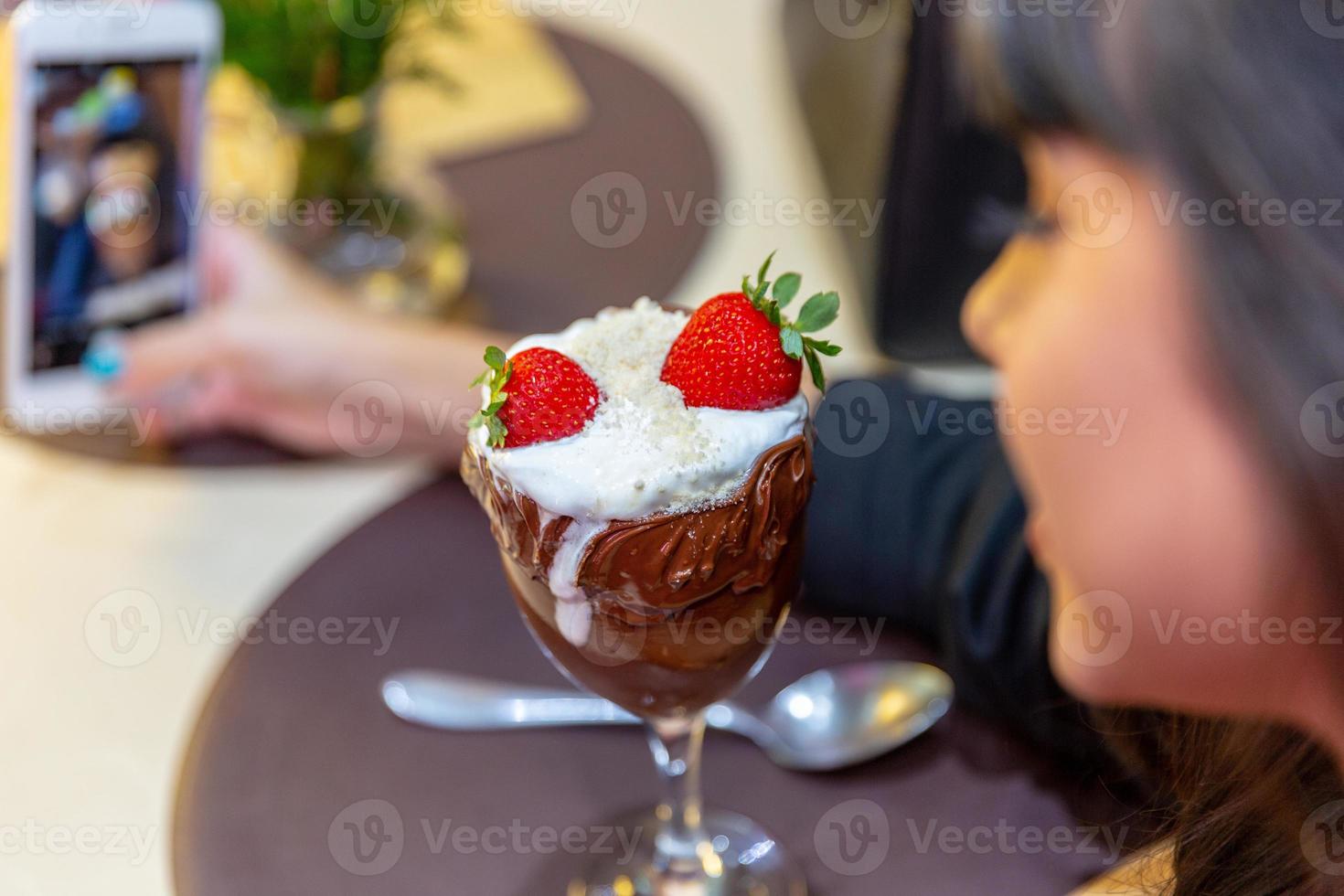 sorvete branco mistura morango com altas calorias, pode engordar, foco suave, desfocado. delicioso sundae de baunilha ou chocolate com morango. foto