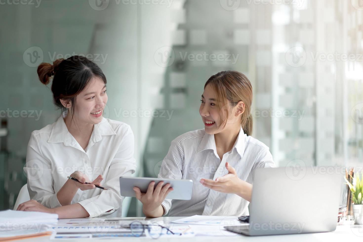 duas mulheres de negócios asiáticas trabalham juntas para fazer o trabalho no escritório. foto