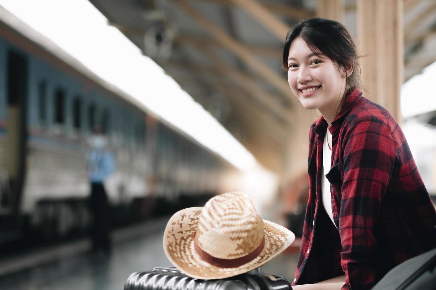 mulher jovem viajante procurando amigo planejando viagem na estação de trem. conceito de estilo de vida de verão e viagens foto