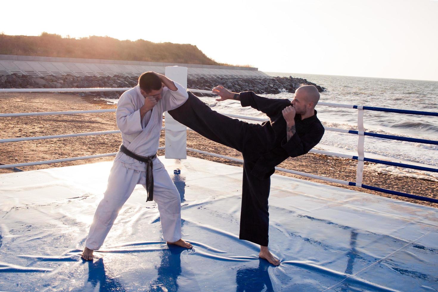 lutadores de karatê estão lutando no ringue de boxe de praia de manhã foto