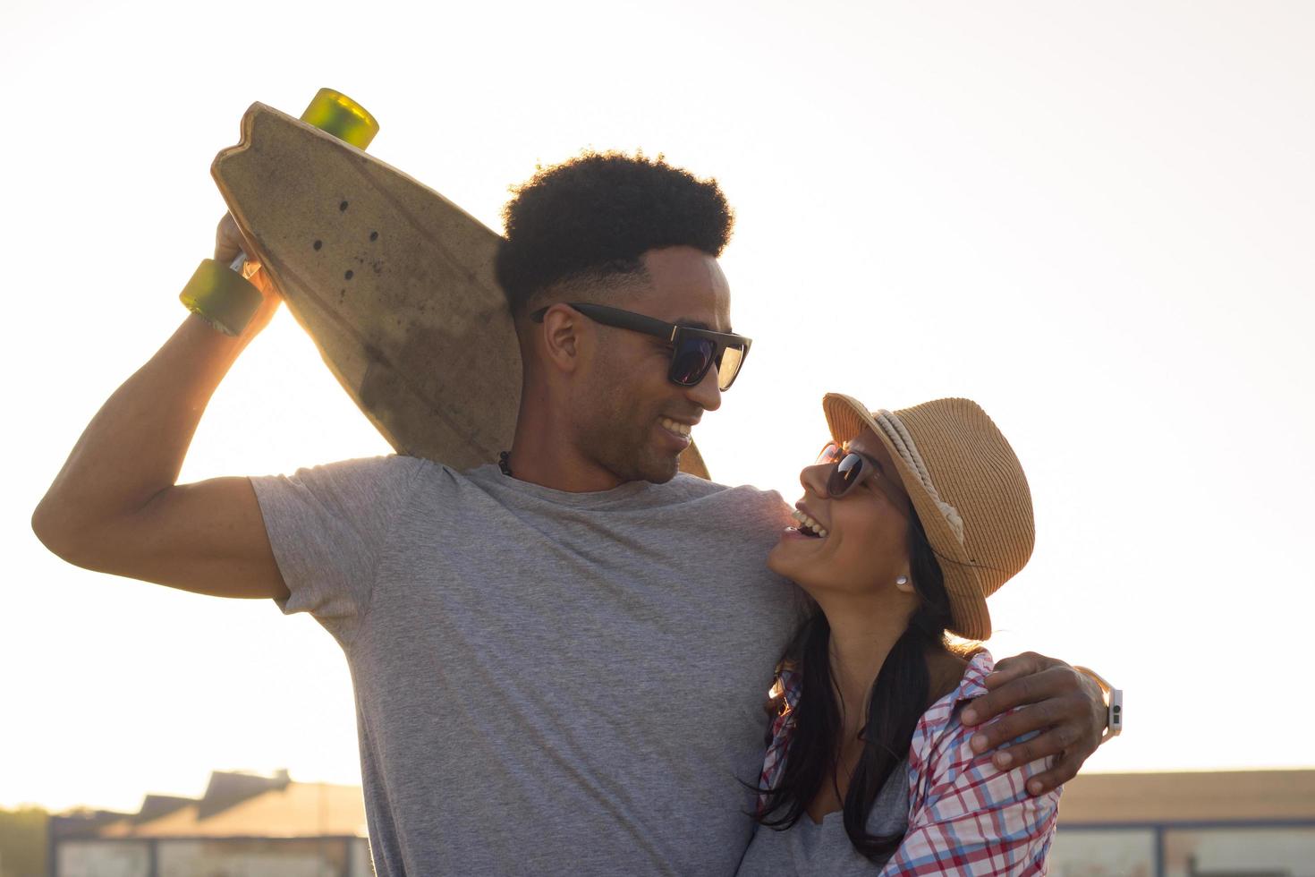 casal jovem feliz andando de skate durante o nascer do sol foto