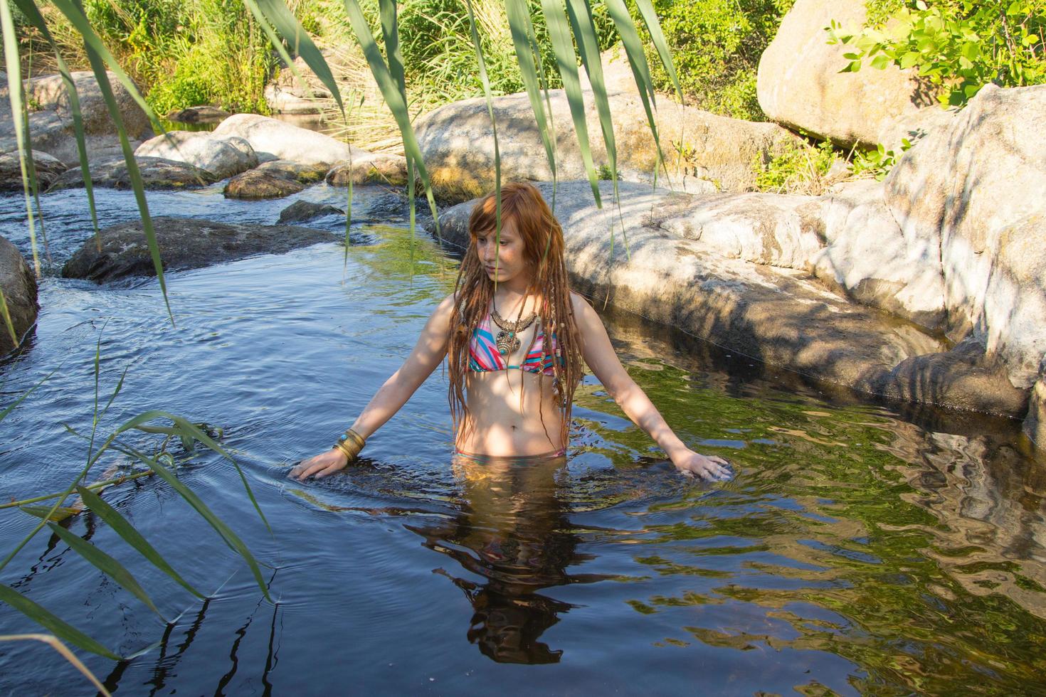 jovem mulher bonita com dreadlocks nadar no rio da montanha no verão, mulher ruiva na lagoa foto