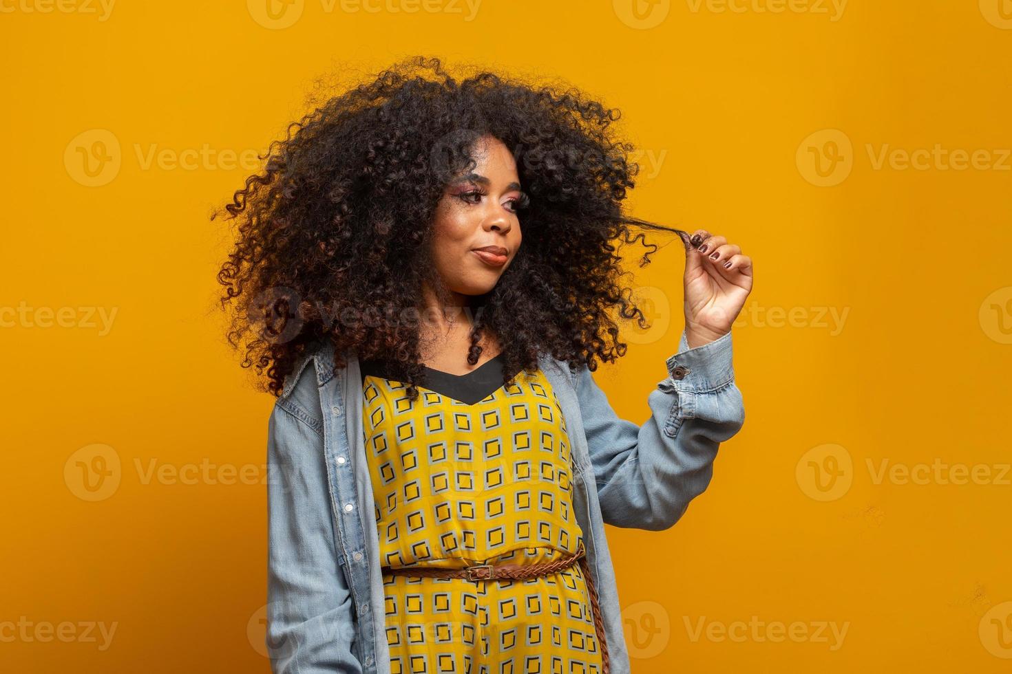 retrato da beleza da mulher afro-americana com penteado afro e maquiagem glamour. mulher brasileira. mestiço. cabelo encaracolado. Penteado. fundo amarelo. foto