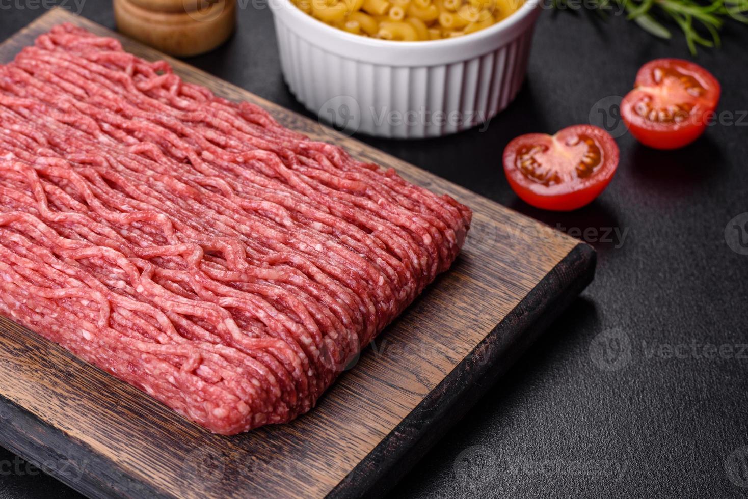 carne moída crua fresca com especiarias e ervas em um fundo escuro de concreto foto