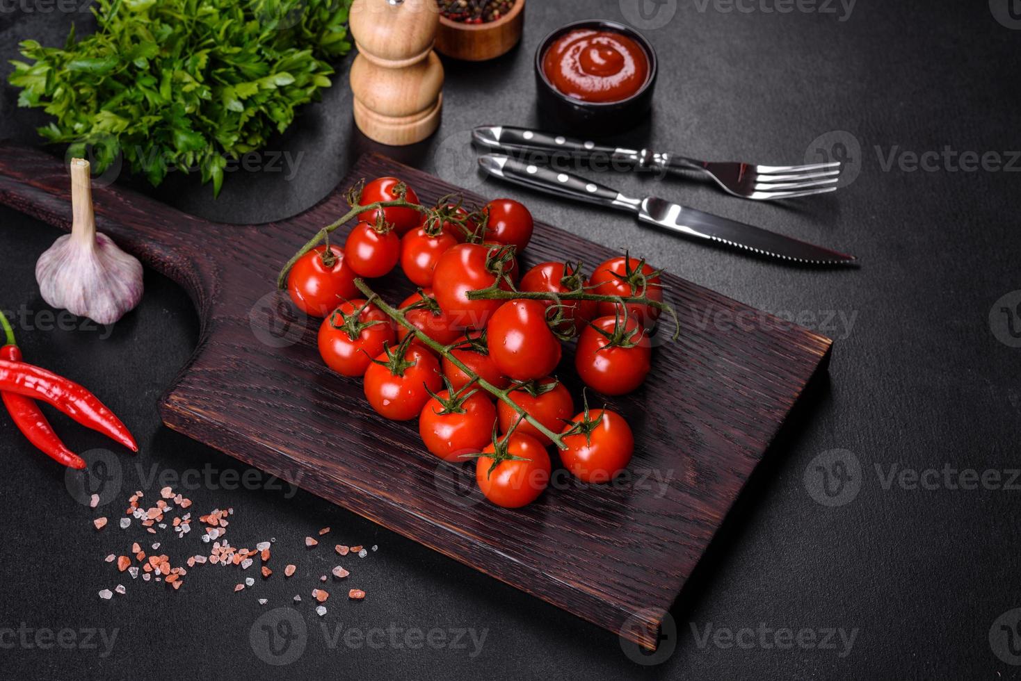 tomate cereja fresco em um fundo preto com especiarias foto