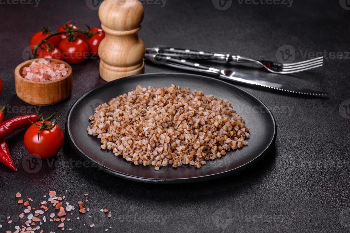 delicioso mingau de trigo sarraceno cozido fresco com legumes e especiarias em um prato preto foto