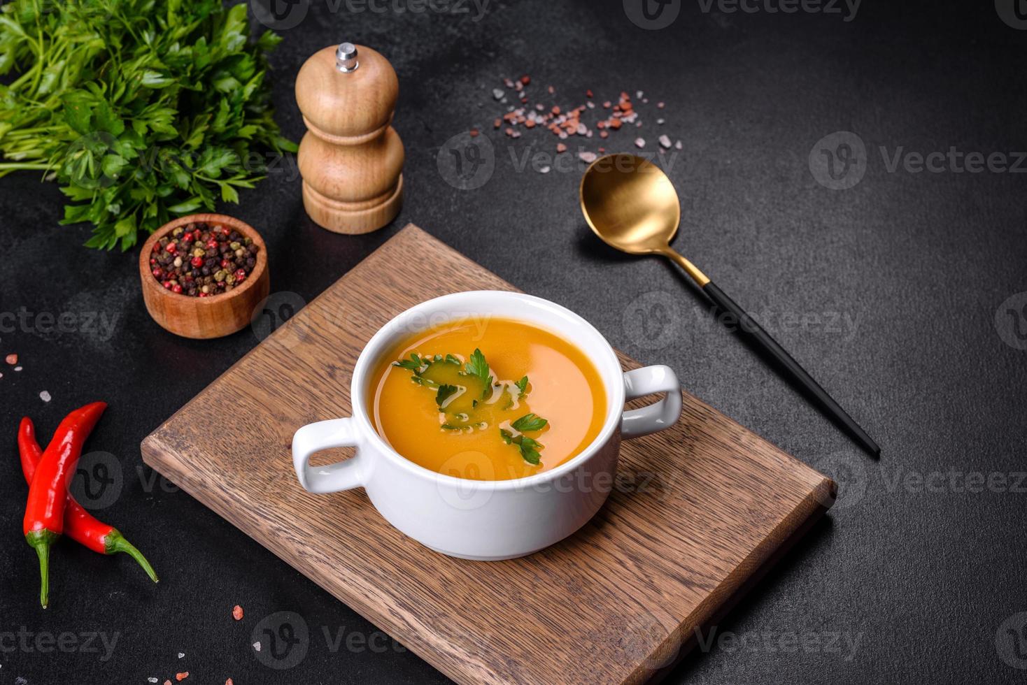 deliciosa sopa de purê de abóbora fresca decorada com salsa em um prato branco foto