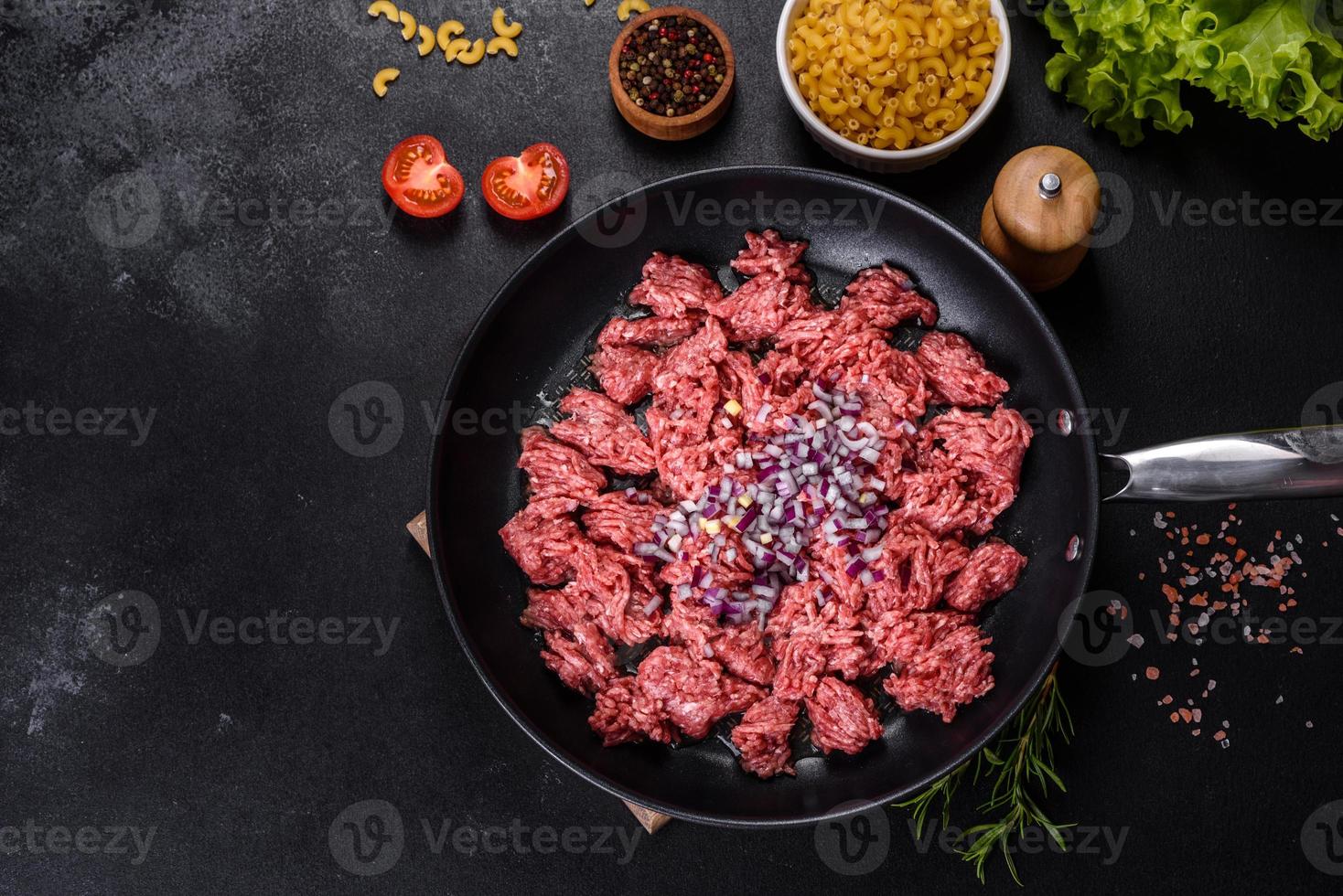 carne moída crua fresca com especiarias e ervas em um fundo escuro de concreto foto