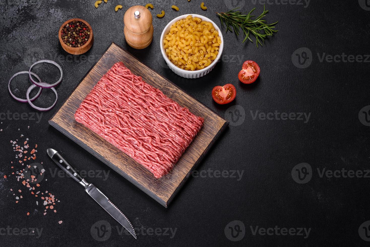 carne moída crua fresca com especiarias e ervas em um fundo escuro de concreto foto