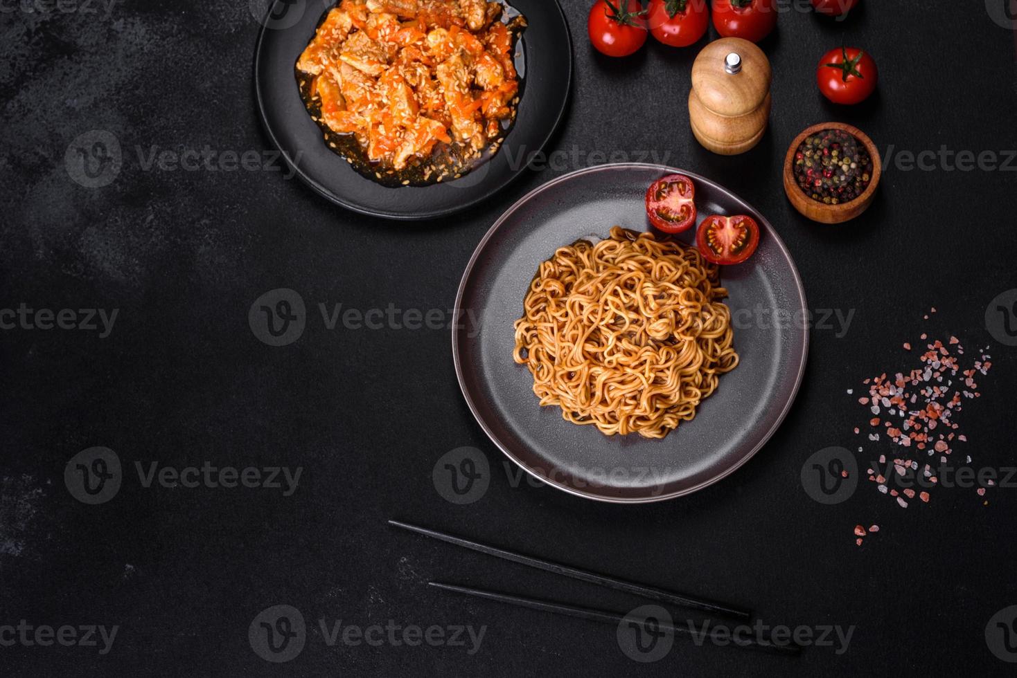 prato de macarrão e frango tailandês em um fundo preto de concreto com pauzinhos chineses e espaço de cópia foto