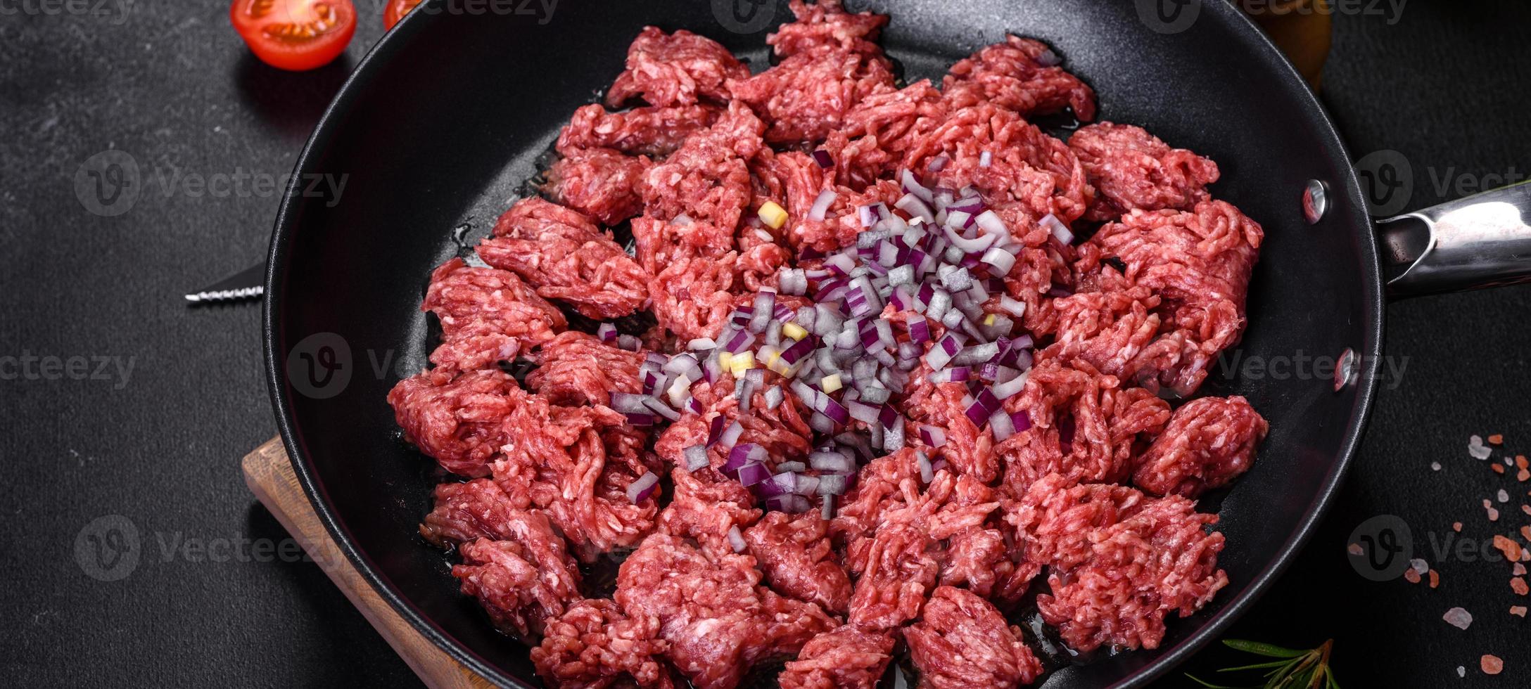 carne moída crua fresca com especiarias e ervas em um fundo escuro de concreto foto