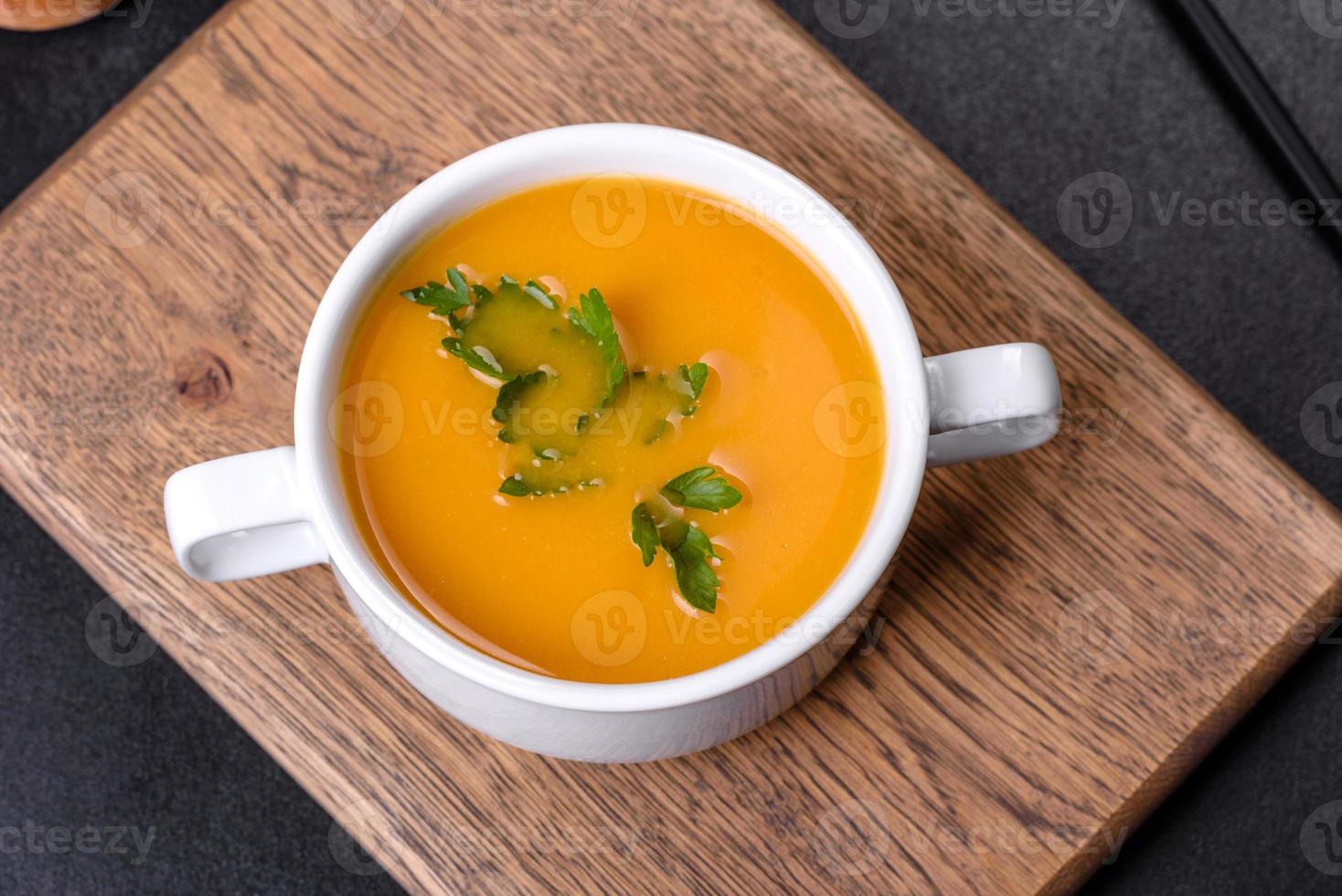 deliciosa sopa de purê de abóbora fresca decorada com salsa em um prato branco foto