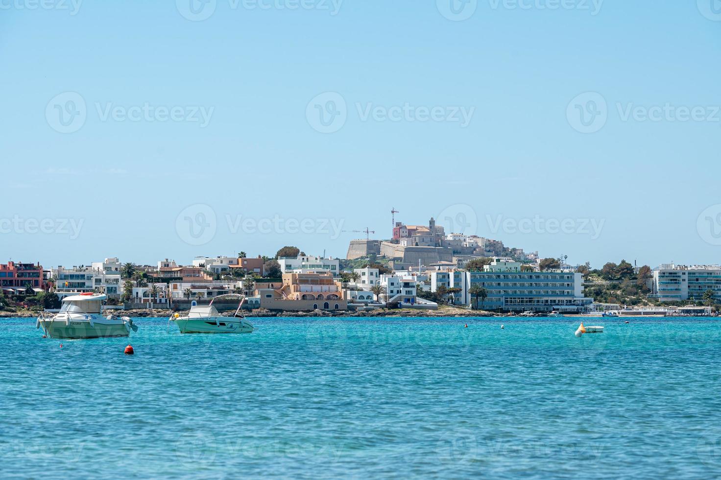 barcos nas águas azul-turquesa do mediterrâneo na baía de talamanca em ibiza, espanha. foto