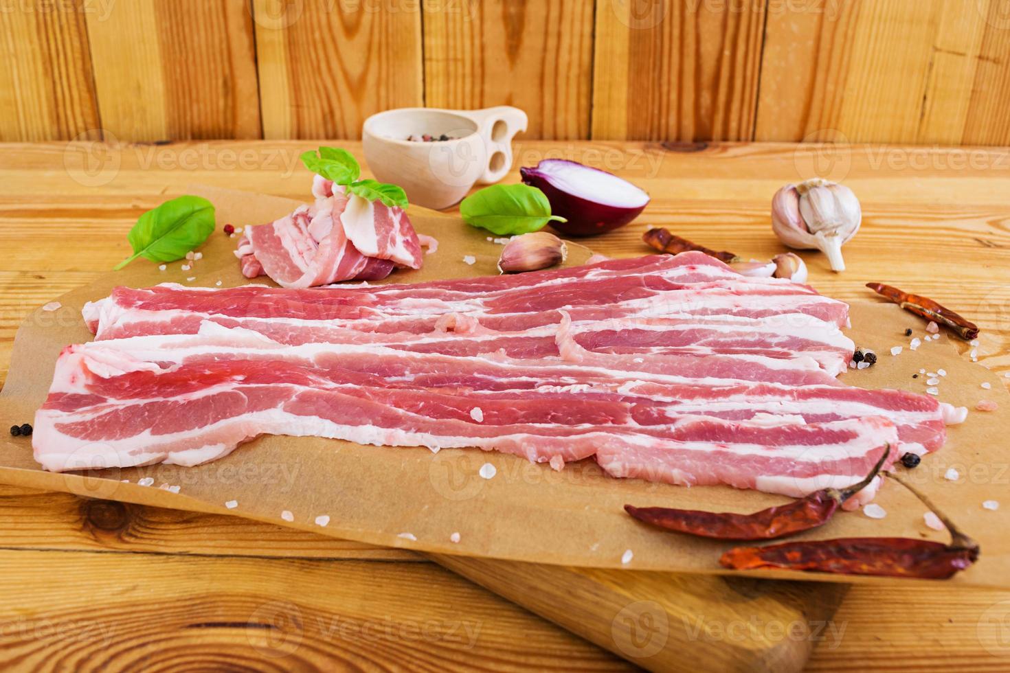 bacon fatiado fresco com especiarias em fundo branco foto