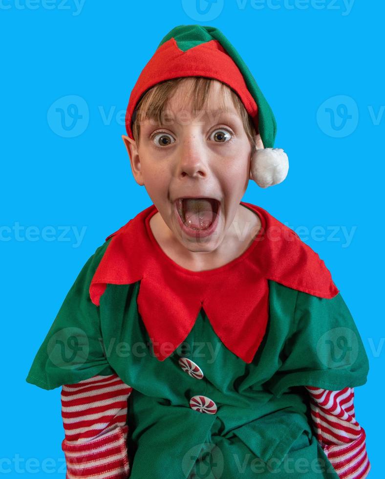 menino surpreso vestido como elfo de natal em fundo de tela azul foto