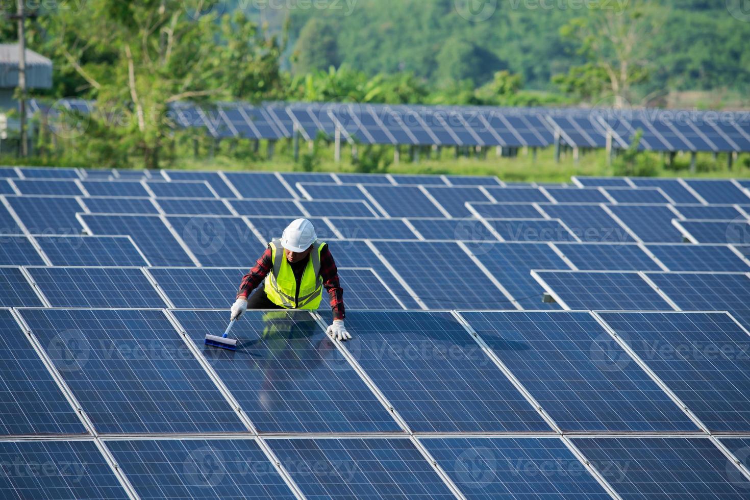 limpeza de painéis solares por trabalhadores em segurança uniforme na fazenda solar foto