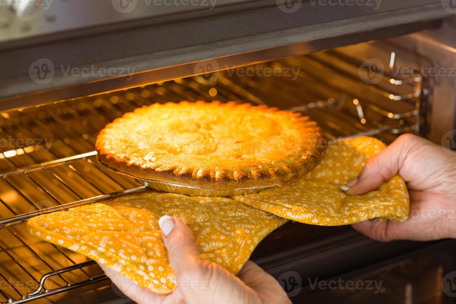 mulher tirando torta fresca do forno foto