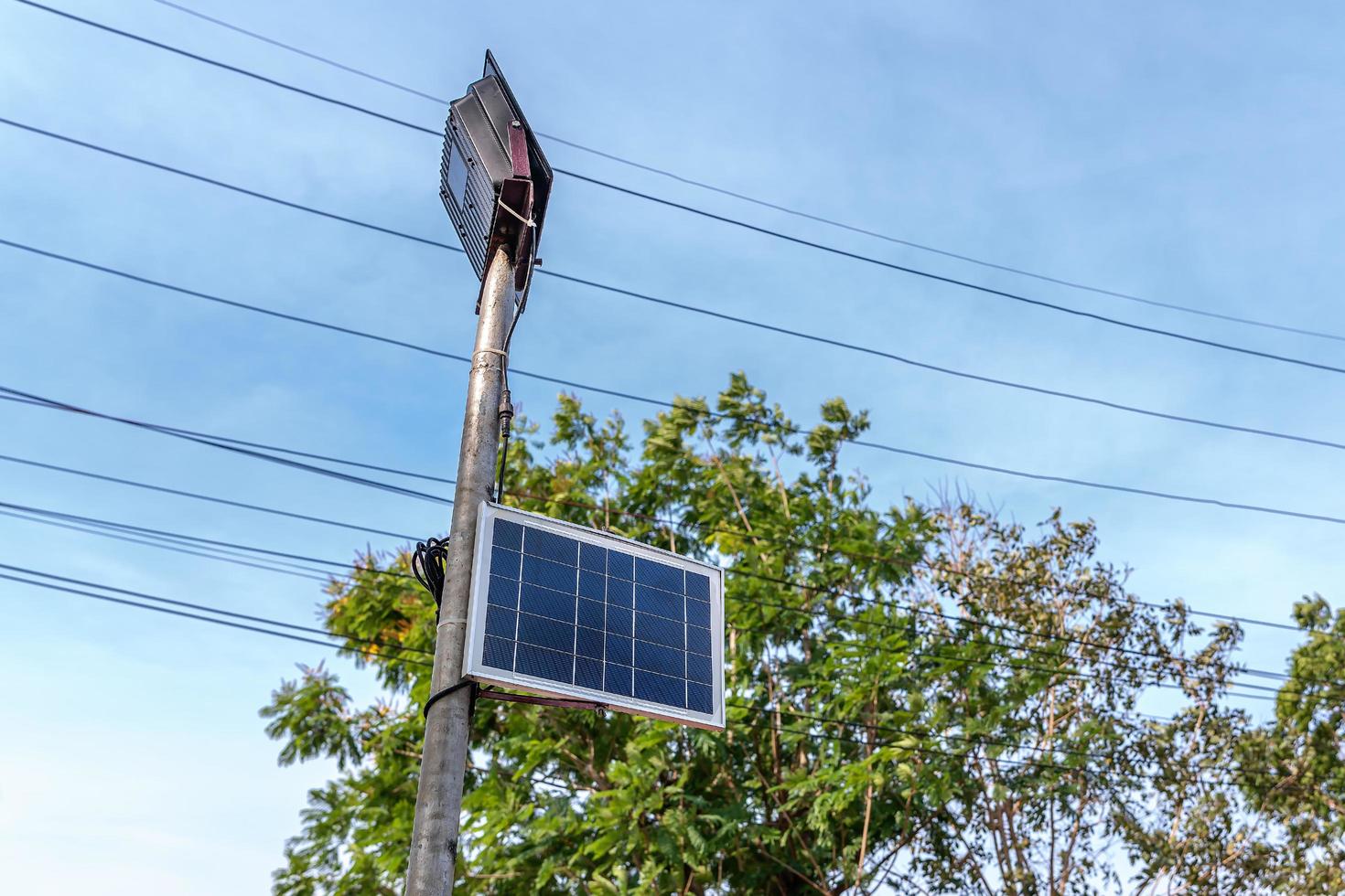 pequeno painel solar para luz na rua ou parque com árvore verde e céu azul. poste de iluminação ao ar livre com energia de painel solar de tamanho pequeno por si só, nova tecnologia e tendência de energia para área pública foto