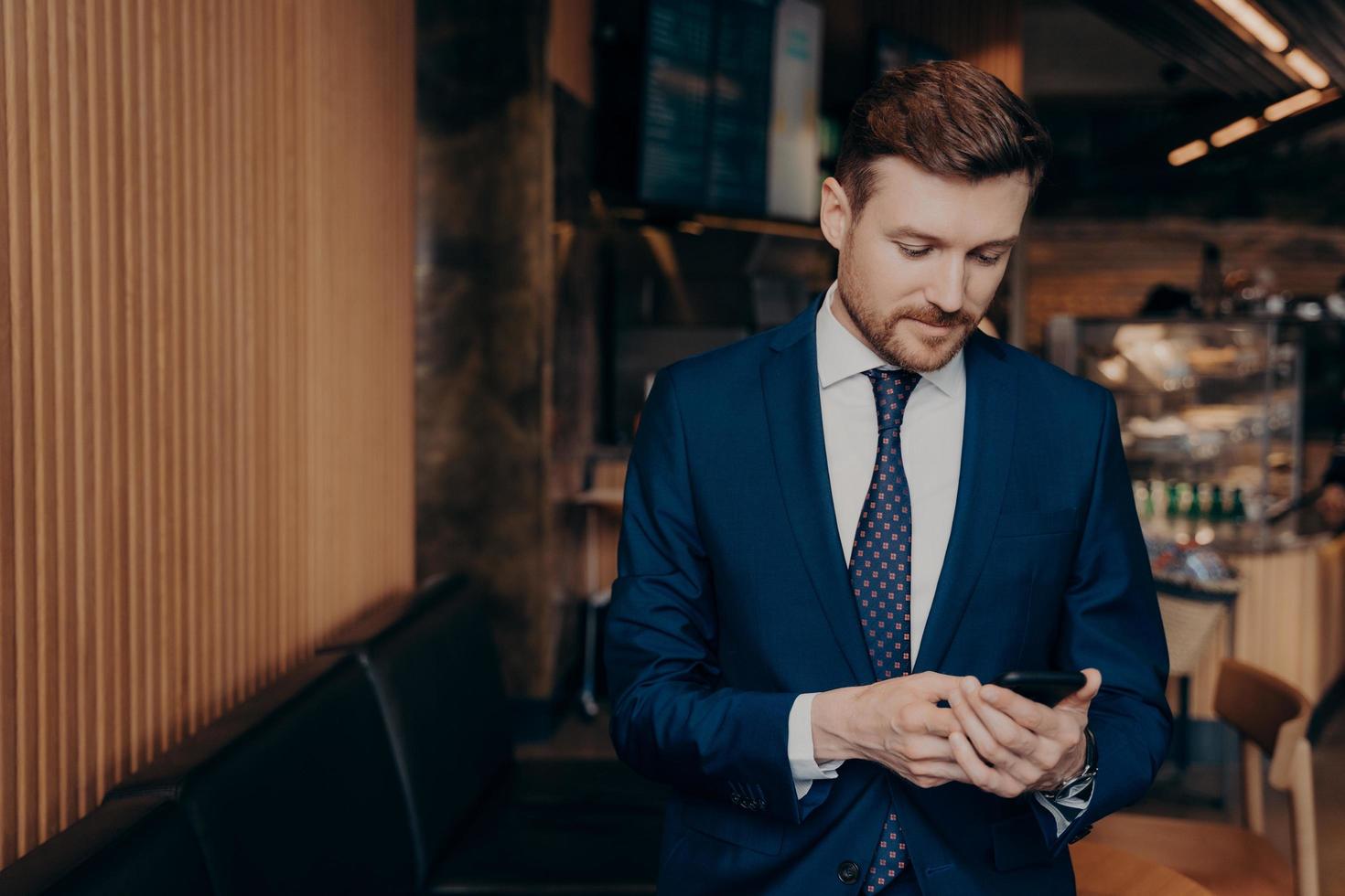 investidor masculino de terno azul usando smartphone no restaurante foto