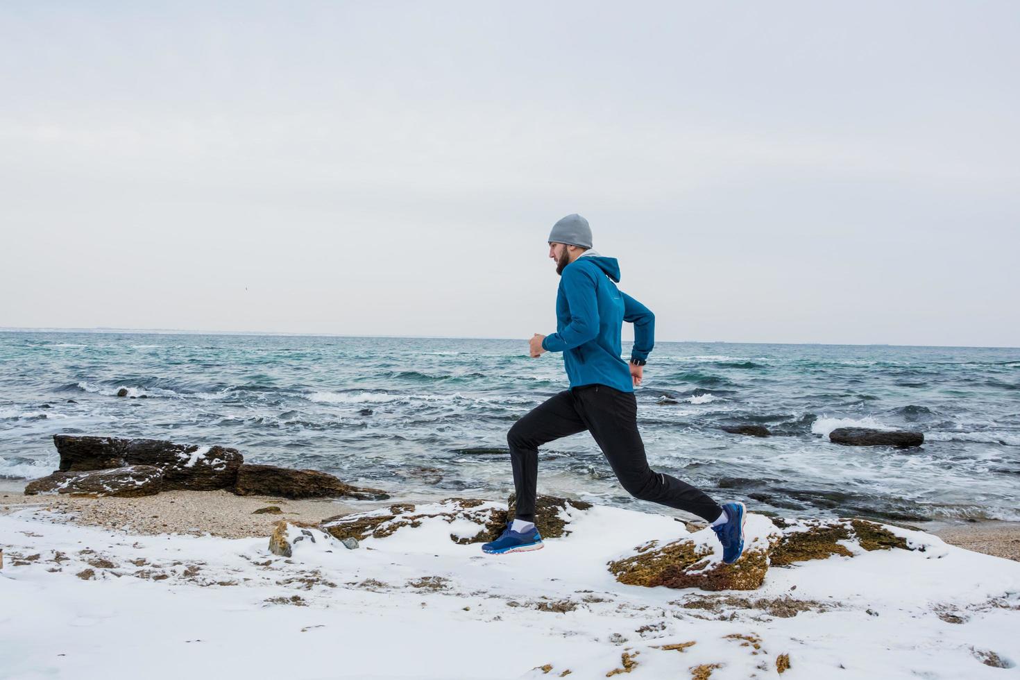 jovem corredor masculino treinando ao ar livre em tempos de inverno, homem correndo na neve foto