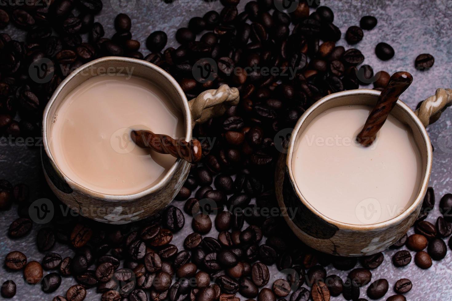 duas canecas de café com grãos de café em um pano de fundo escuro. foto