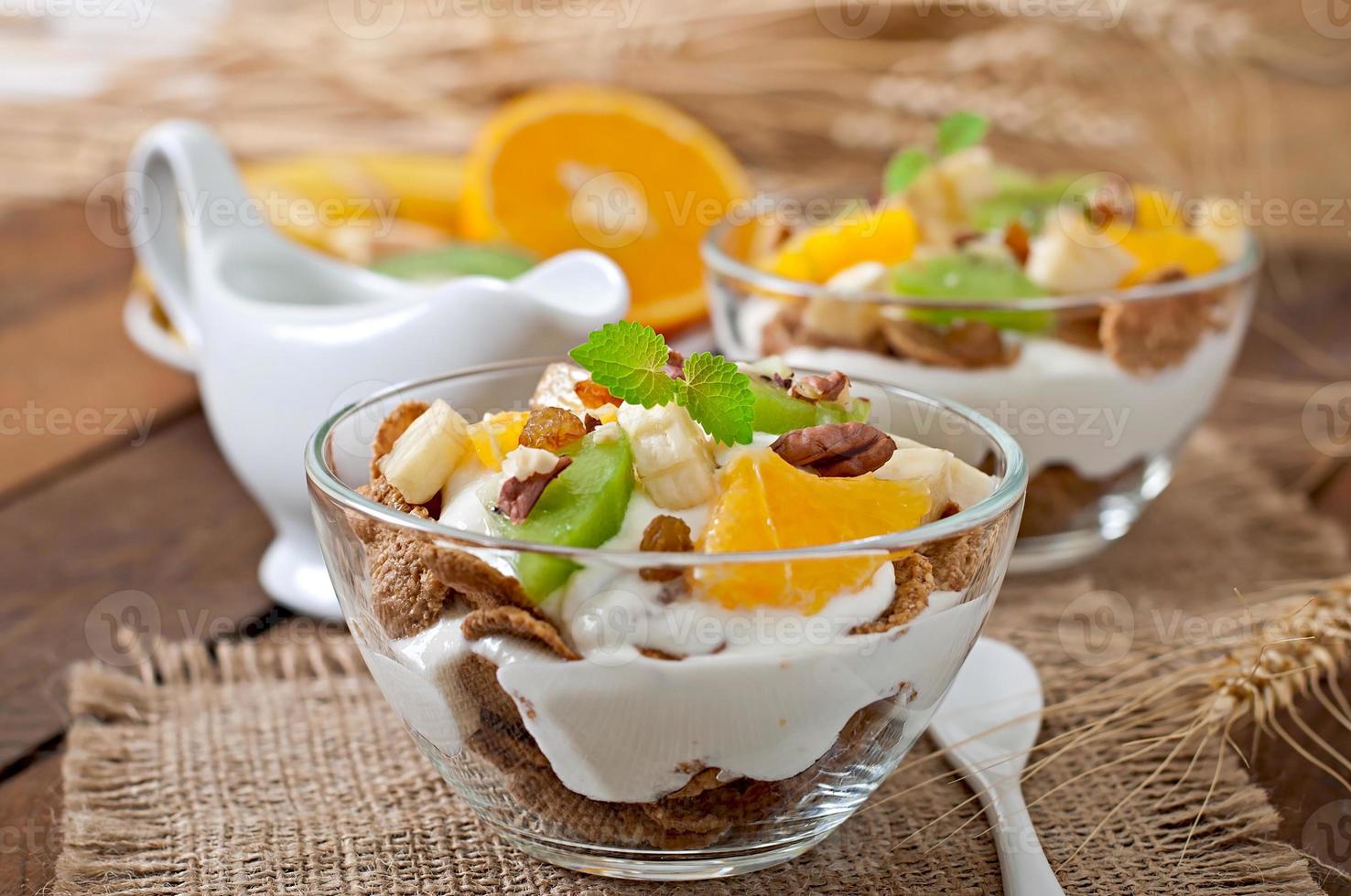 sobremesa saudável com muesli e frutas em uma tigela de vidro em cima da mesa foto