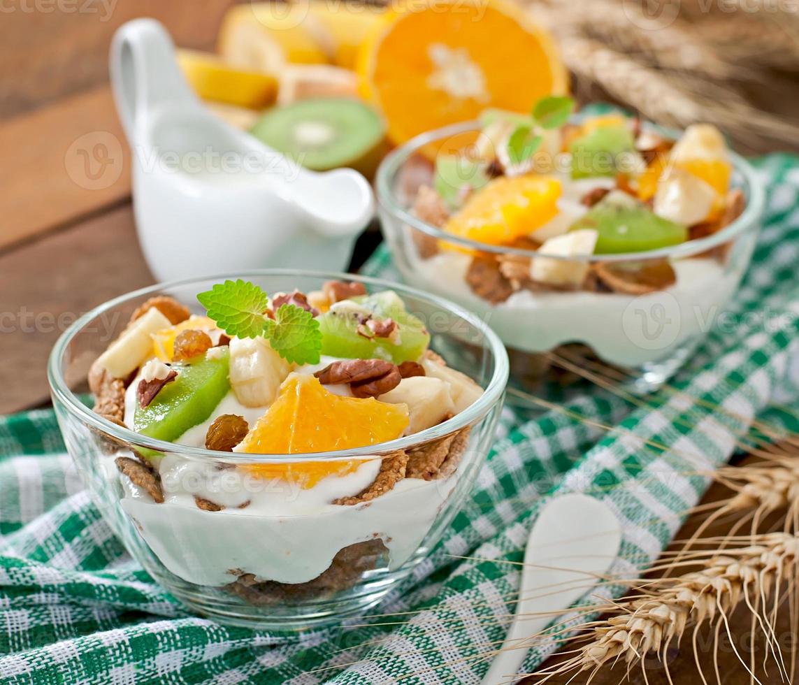 sobremesa saudável com muesli e frutas em uma tigela de vidro em cima da mesa foto