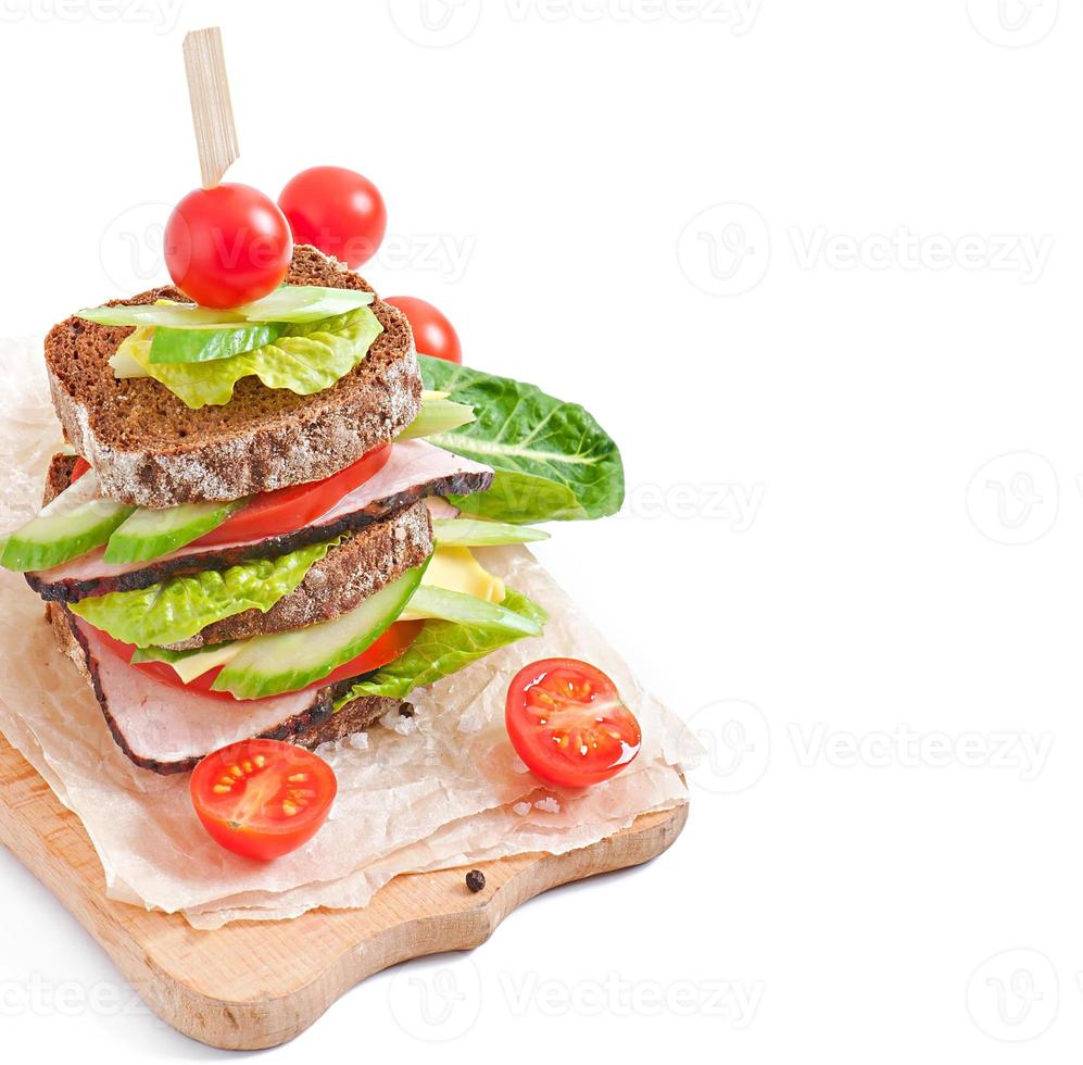 sanduíche com presunto e legumes frescos em um fundo de madeira foto