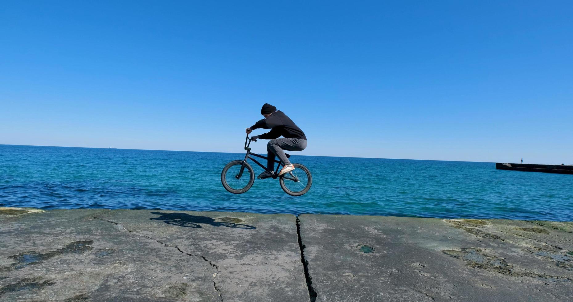 jovem macho com skate relaxante perto do mar foto