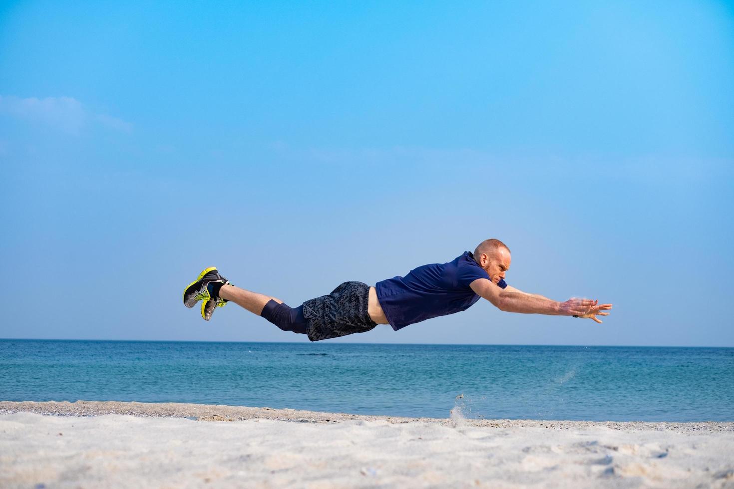 jovem atleta masculino treinando em dia ensolarado na praia foto