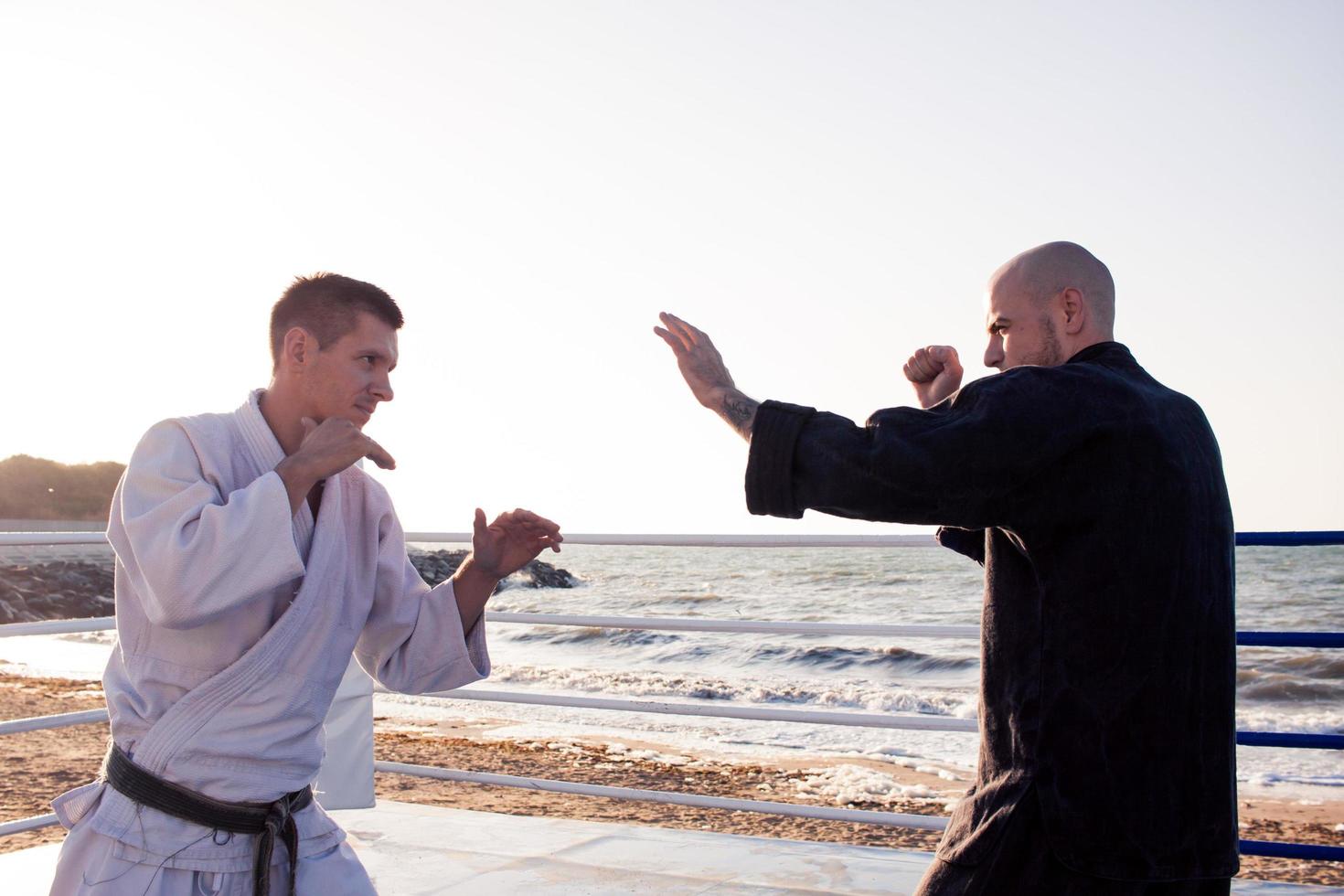 lutadores de karatê estão lutando no ringue de boxe de praia de manhã foto