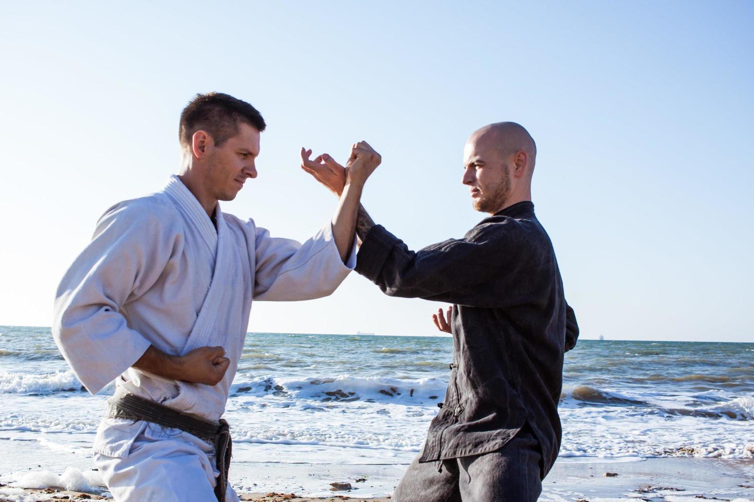 lutadores de karatê estão lutando no ringue de boxe de praia de manhã foto