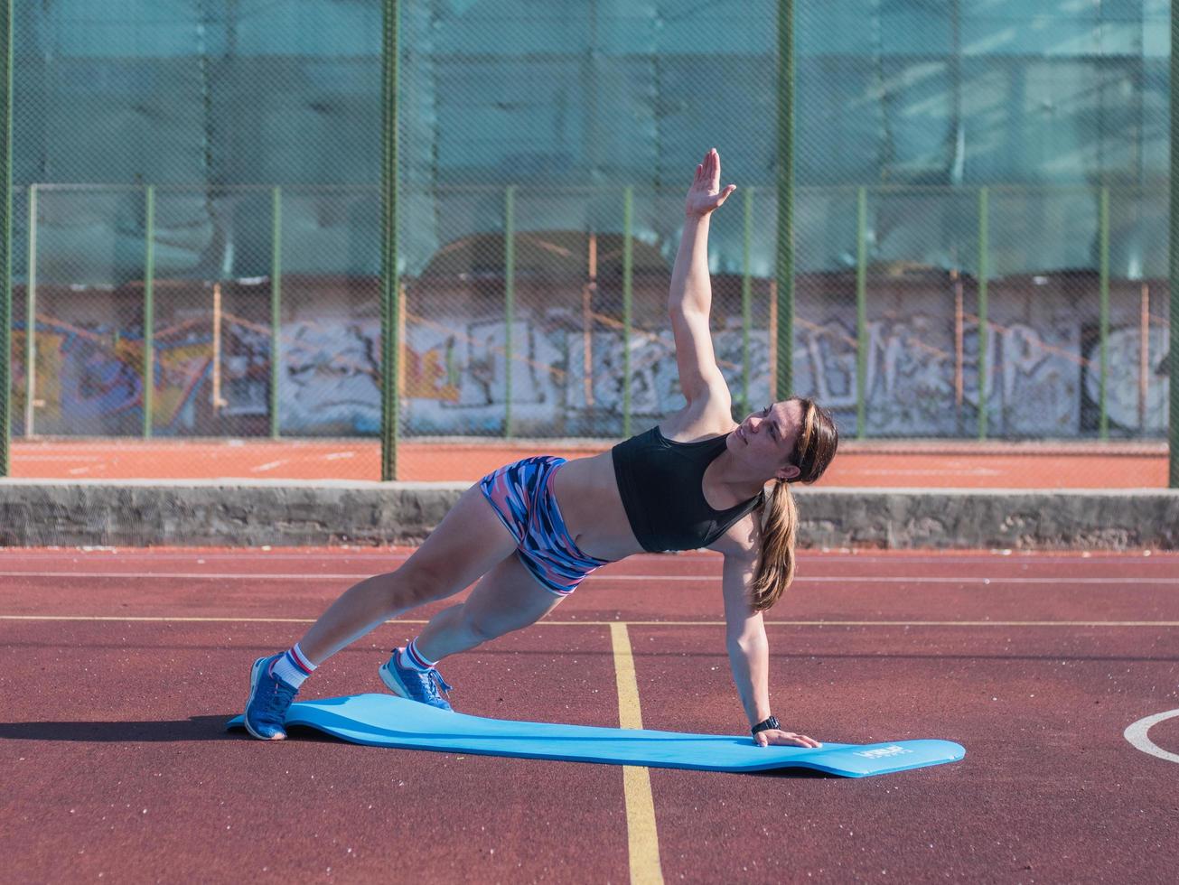jovem mulher forte treinando ao ar livre no verão, atleta profissional feminina faz exercícios no parque foto