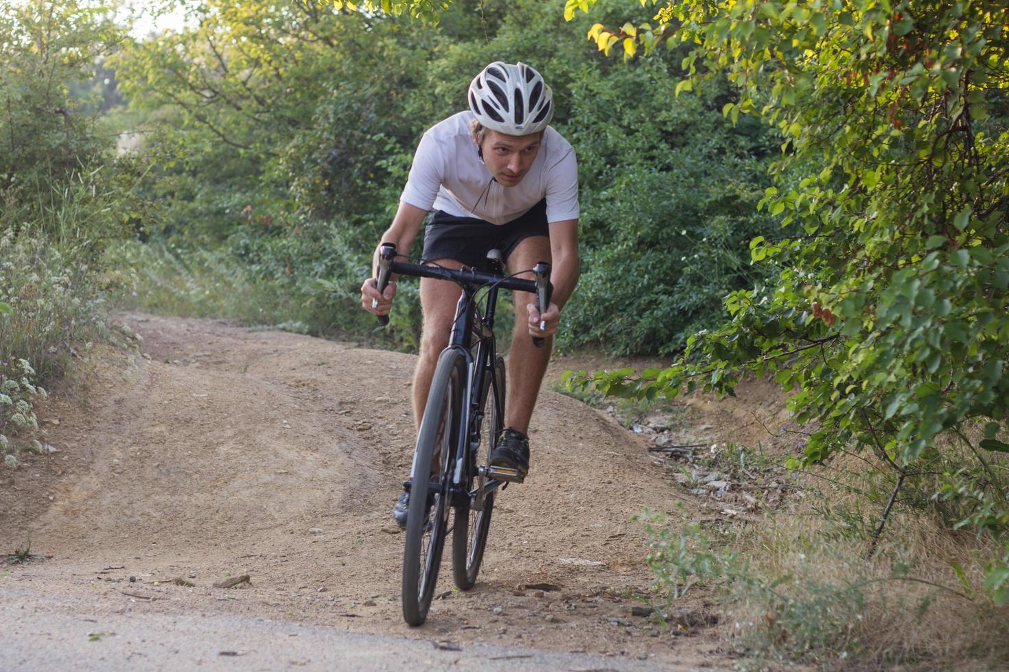 ciclista em passeio de bicicleta de ciclocross profissional em declive, pinheiro e fundo do lago foto