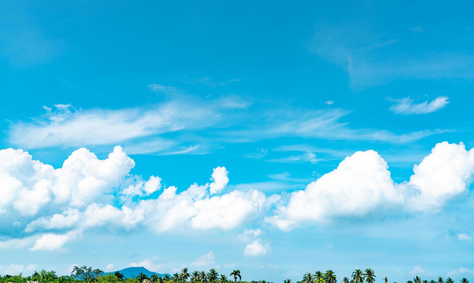 lindo céu azul e nuvens cumulus brancas contra coqueiro e montanha em dia feliz e relaxado. passar o tempo no conceito de férias de verão tropical. plano de fundo para viagens de verão. paisagem de nuvens. foto