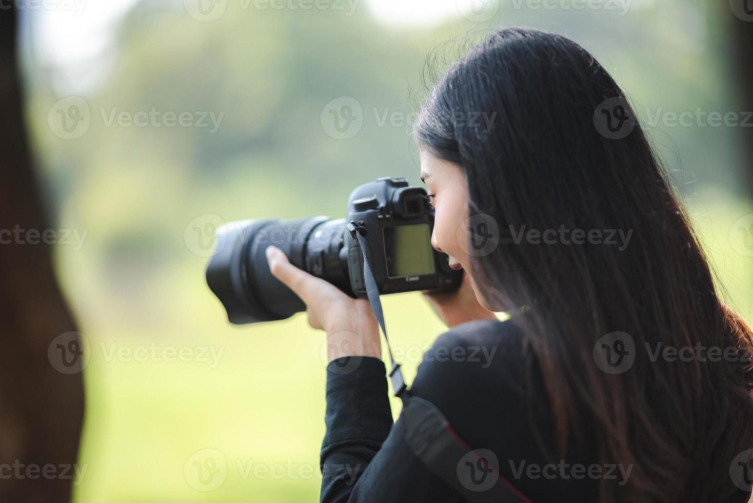 mulher jovem fotógrafo asiático com tiro de tiro de câmera digital de alta tecnologia foto
