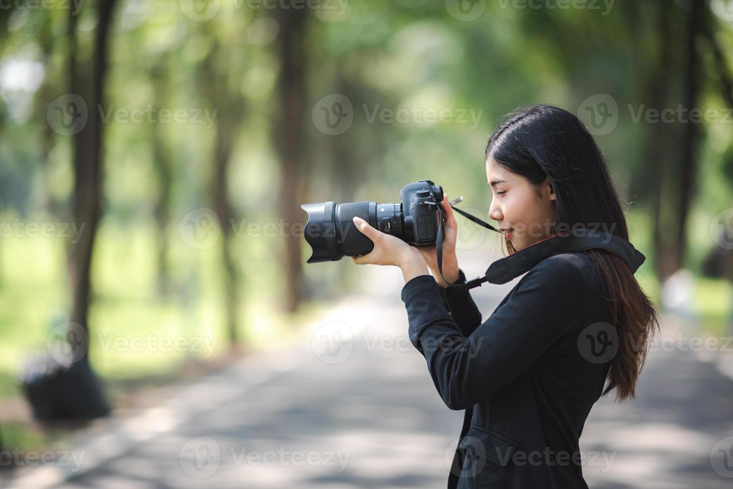 mulher jovem fotógrafo asiático com tiro de tiro de câmera digital de alta tecnologia foto